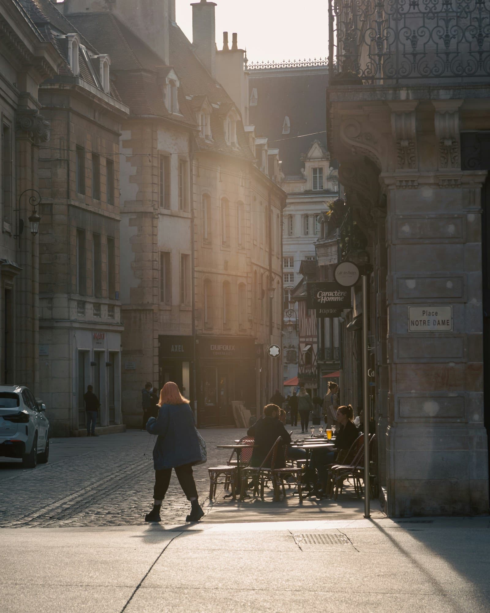 An old European street at sunset, café terraces full and stone facades glowing