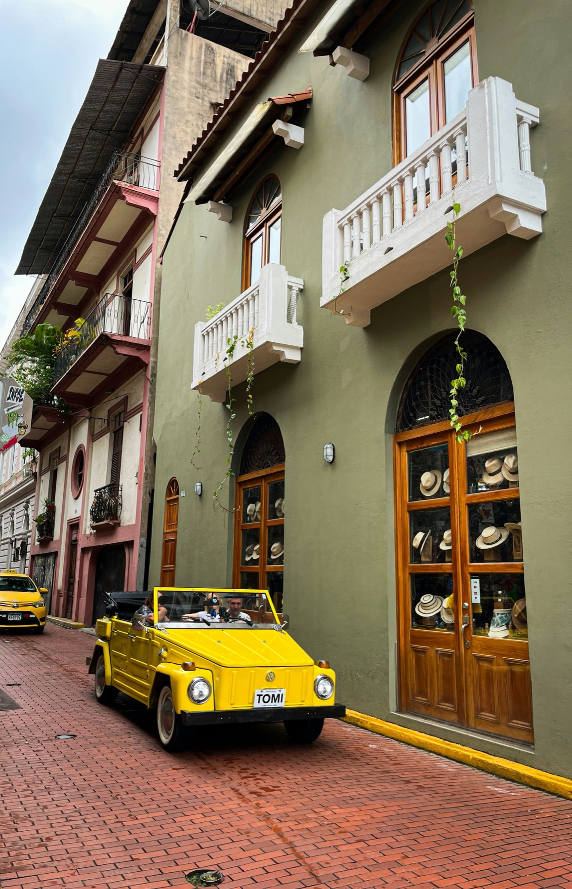 A bright yellow vintage convertible parked on a colorful old-town cobblestone street